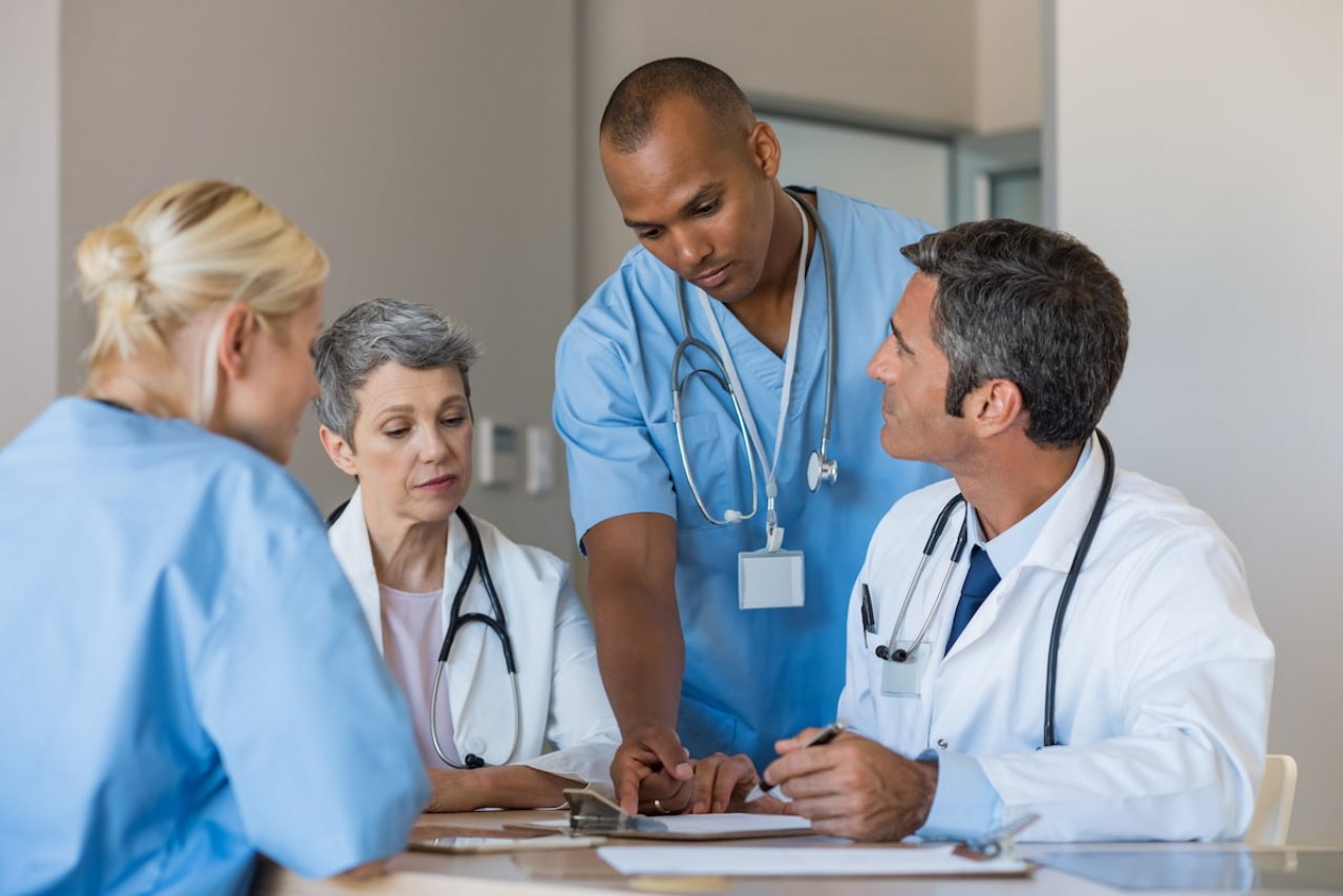 A male doctor, a nuclear medicine specialist, carefully analysing a patient's theranostic imaging scan in a clinical setting.